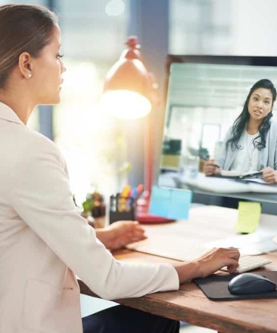Virtual Assistant. Amber Assists. Woman video chatting on computer at a desk. sage and gold